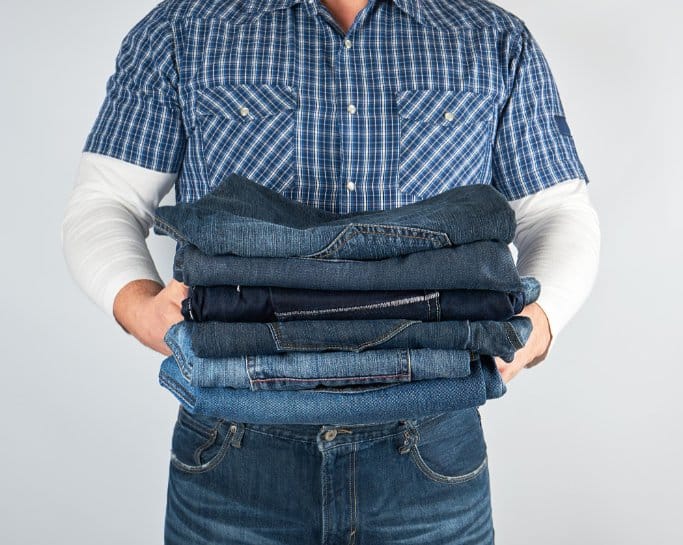 a pile of denim being carried by a professional laundry man ready to be stored