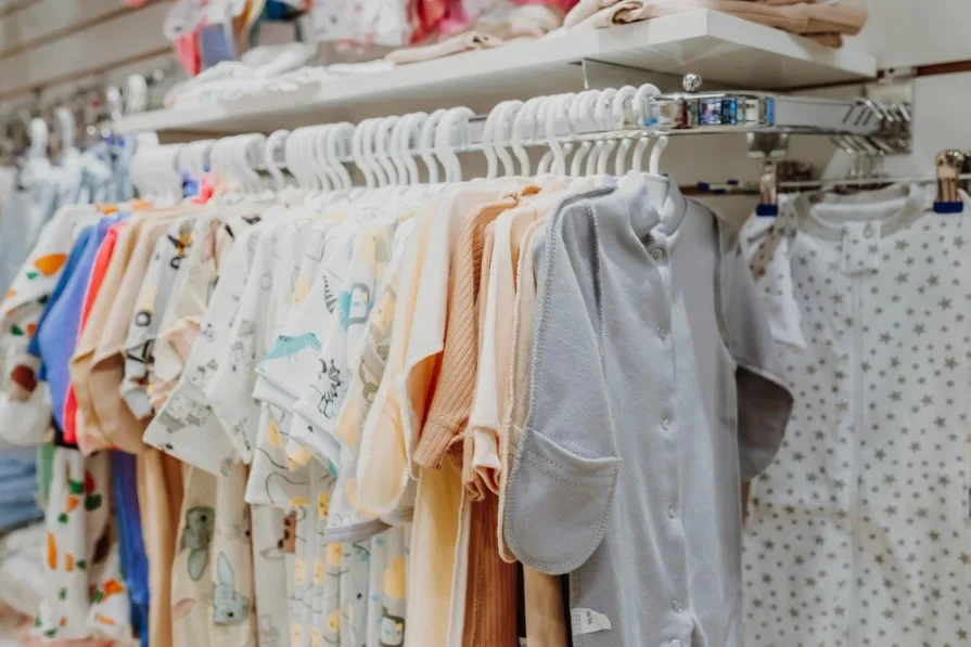 Collection of essential baby clothing items organized by age groups from newborn to 6 months