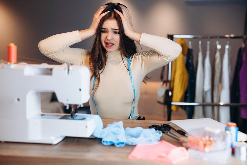 Frustrated woman struggling with sewing machine issues at home sewing table