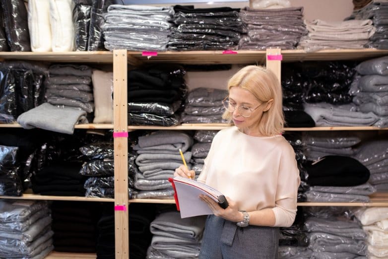 fabric shop inventory with folded garments and textile stacks showing fabric cost management and retail pricing