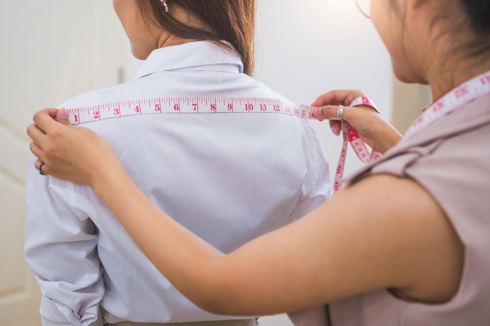Woman taking body measurements with measuring tape for dress fitting