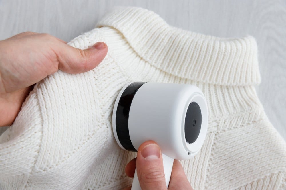 a wool sweater being taken maintained using a lint remover