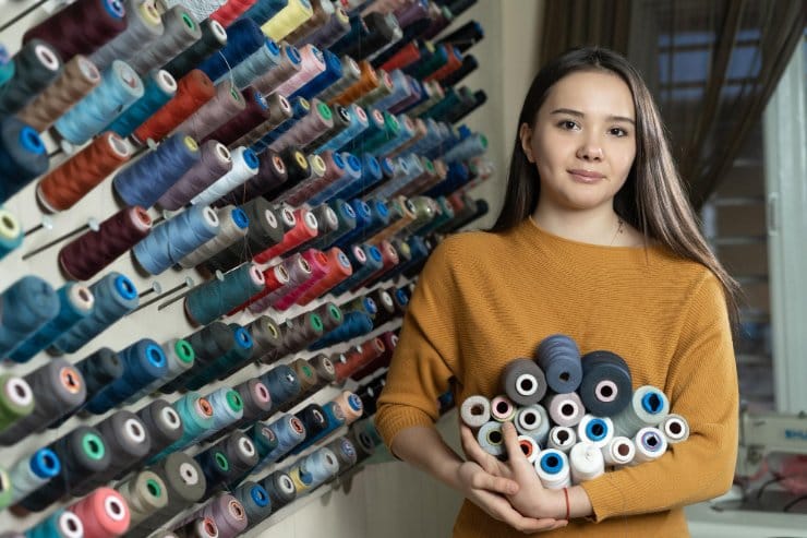 person holding multiple thread spools while selecting sewing supplies in craft store