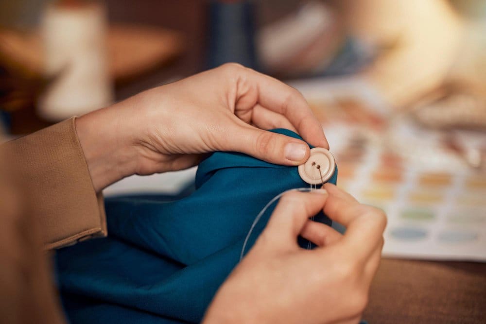 Hand sewing a loose button back onto fabric garment