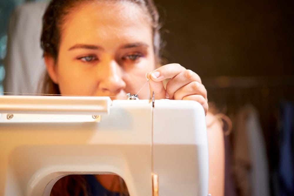 Threading a sewing machine needle carefully before starting a project