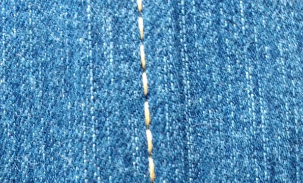 Close up of straight stitching on denim fabric with visible seam detail