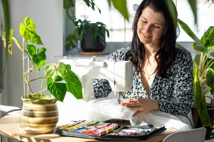 Woman sewing clothing at home in bright natural light