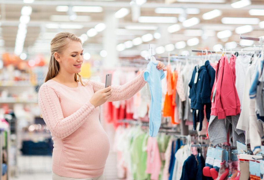 Parent reading fabric labels and checking certifications while shopping for baby clothes