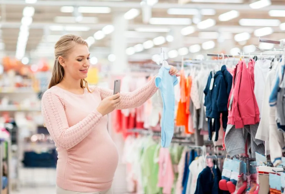 Parent reading fabric labels and checking certifications while shopping for baby clothes