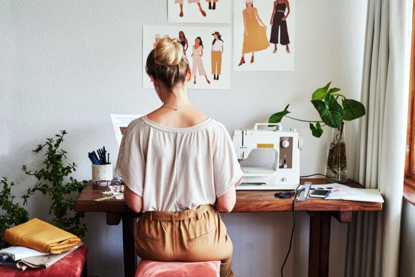Beginner sewing workspace with sewing machine and fashion sketches on wall