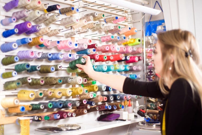 person choosing colorful thread spools in sewing supply store