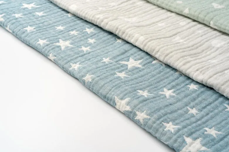 Soft baby clothes made from organic cotton and natural fabrics arranged on a gentle surface