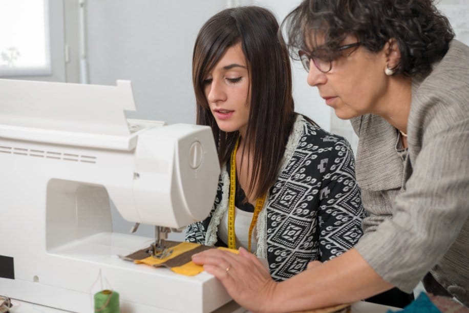 Sewing instructor guiding student while practicing straight stitch technique