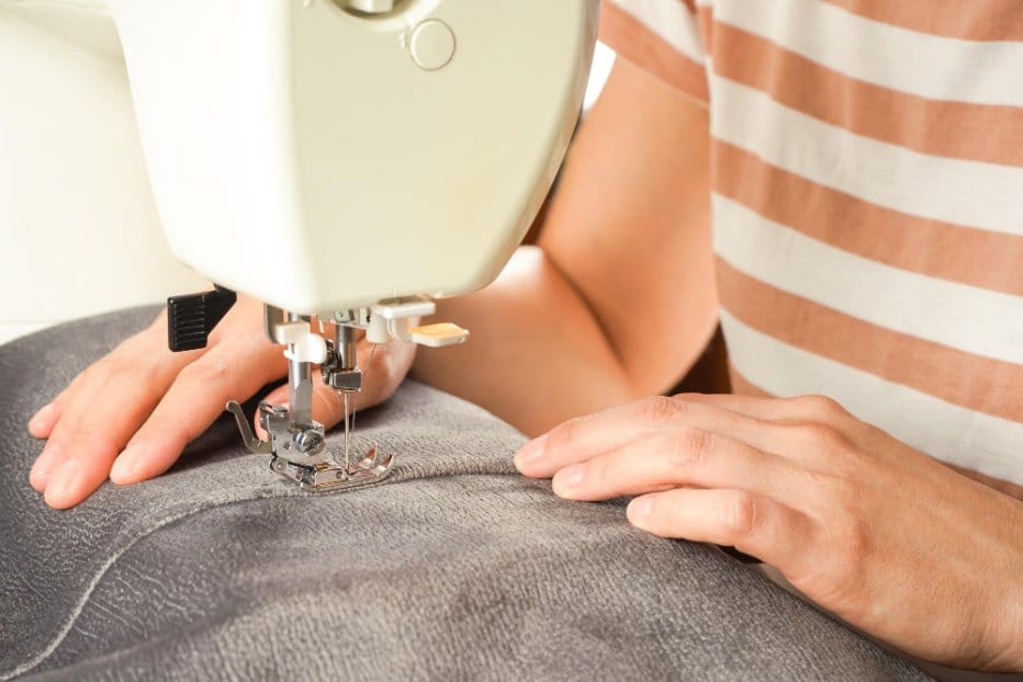 Sewist guiding fabric carefully under sewing machine needle for straight seam