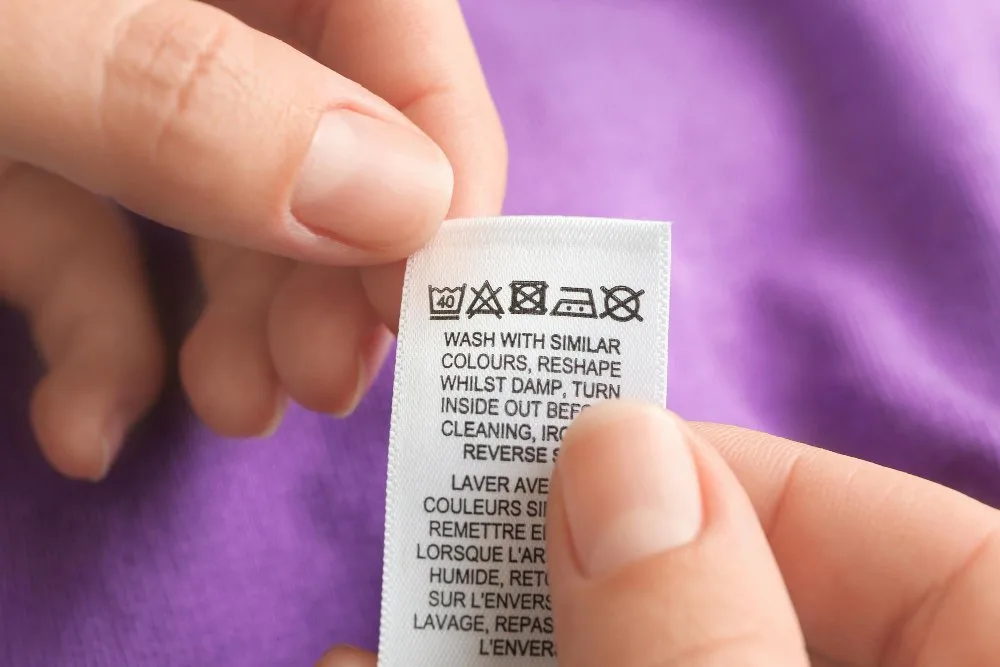 Close-up of a clothing care label showing fiber content percentage and washing instructions