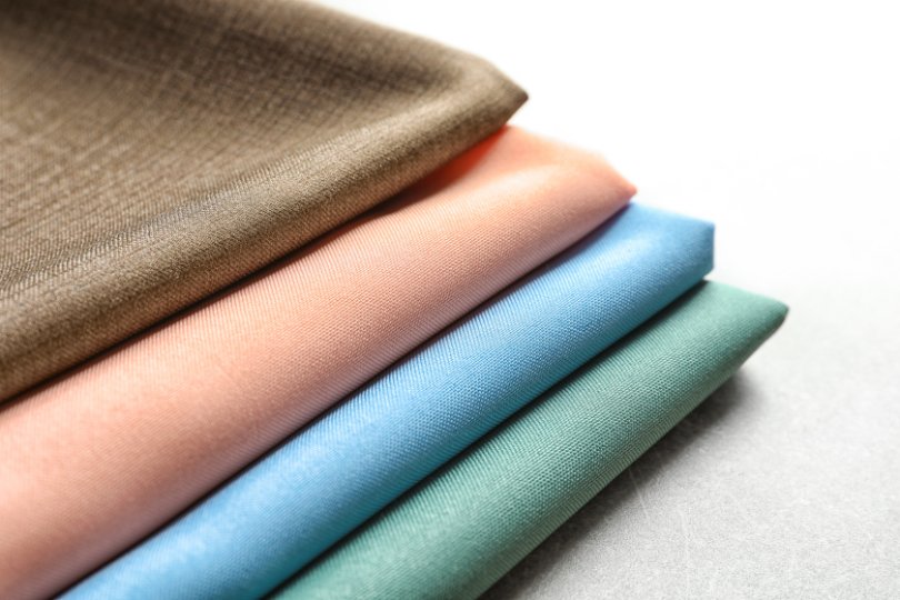 Various fabric swatches including cotton, bamboo, and organic cotton with measuring tools nearby