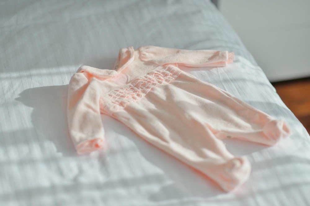 Various safe baby sleepwear options including onesies, sleep sacks, and footed pajamas laid out for comparison