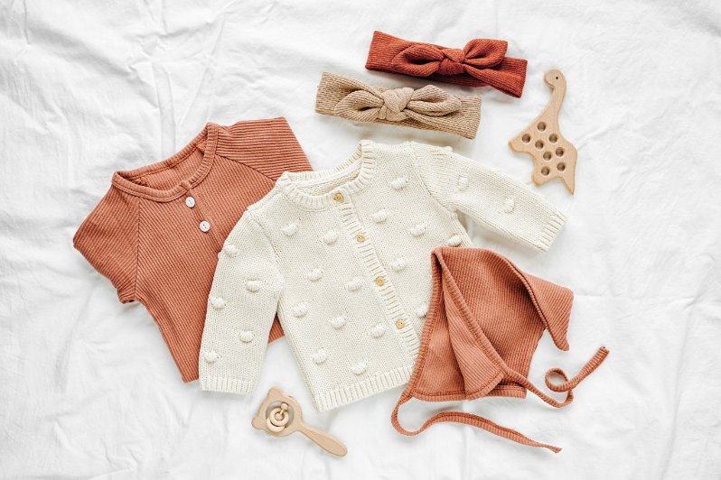 Essential sustainable baby wear items including organic cotton onesies, eco-friendly sleepers, and natural fiber clothing