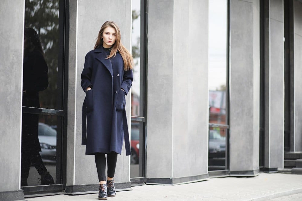 Beautiful woman wearing a coat and standing in front of a building