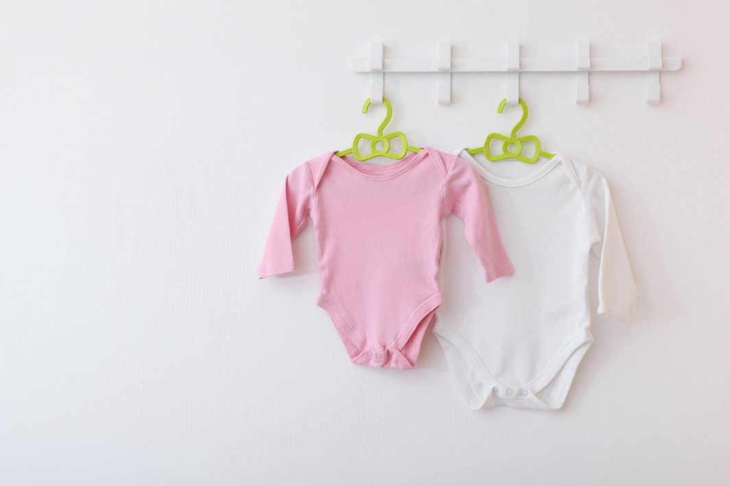 A colorful display of baby rompers and sleepers showing the difference between daytime rompers and nighttime sleepers