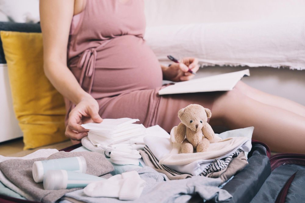 Essential baby layette items laid out including onesies, sleepers, blankets, and basic newborn necessities
