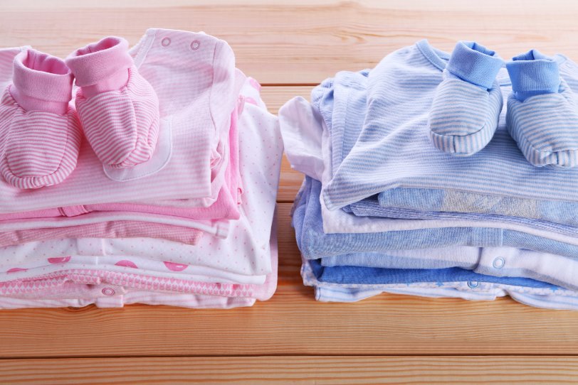 Stack of colorful newborn onesies arranged neatly with care labels visible