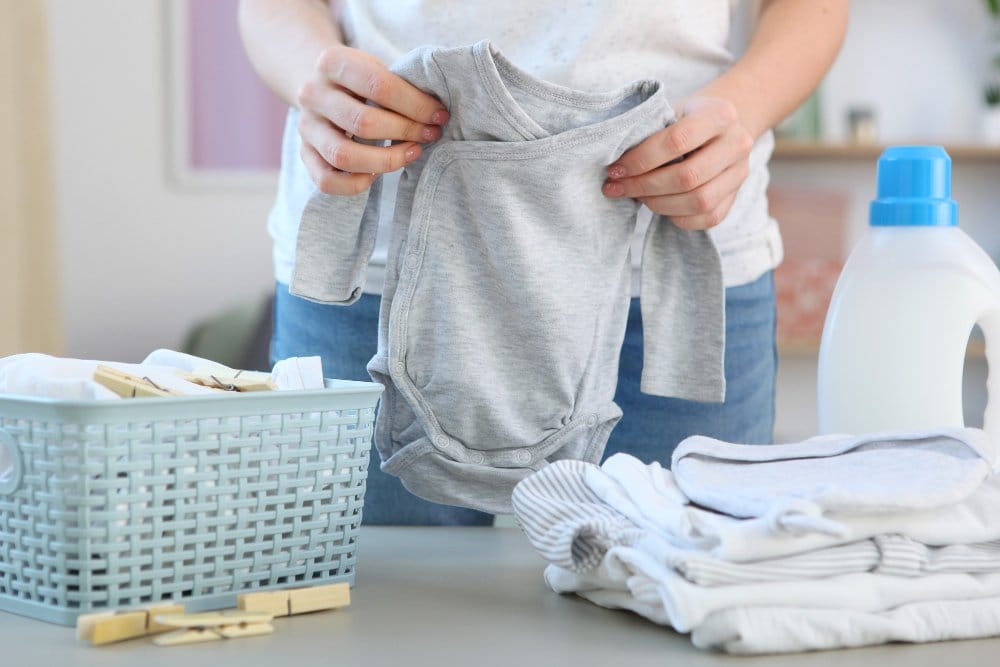 A woman in laundry folding clean and fresh baby clothes after wash