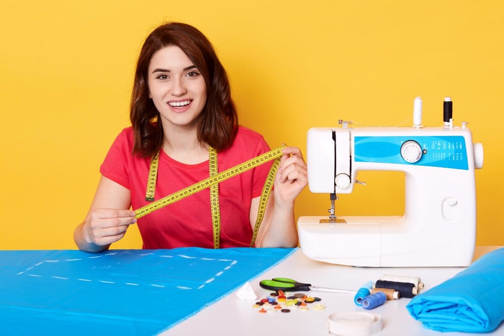 Close up portrait of young creative designer sewing clothes on sewing machine