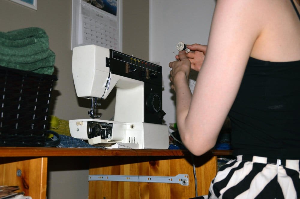 a woman holding a thread troubleshooting a sewing machine