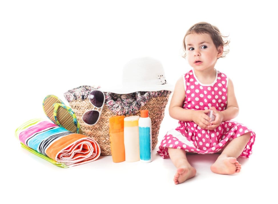 Toddler sitting next to a basket full of accessories ready to go to the beach