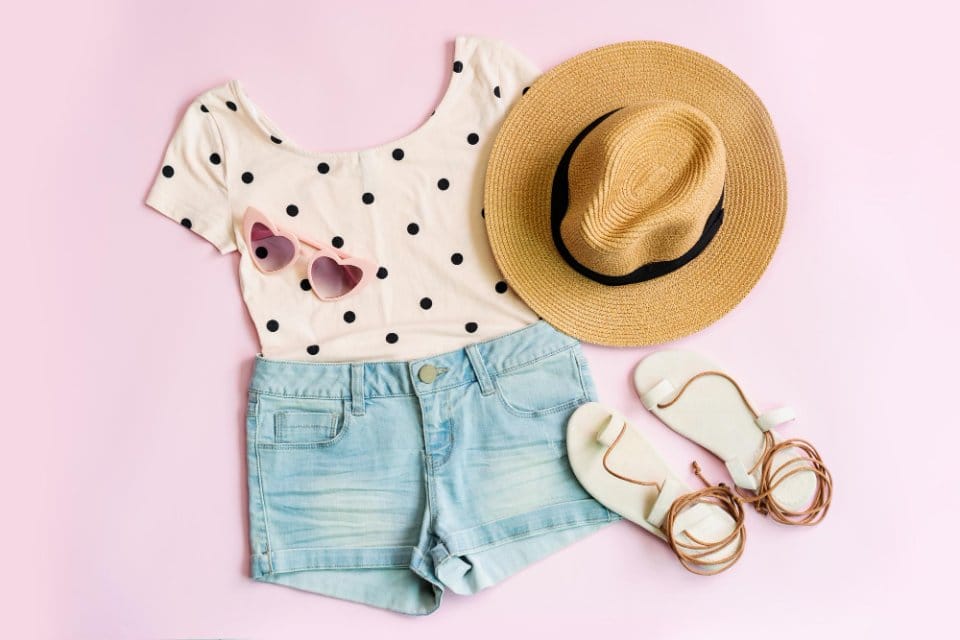 A sunny day with a toddler's summer wardrobe laid out, including lightweight t-shirt, shorts, sandals, and a sun hat