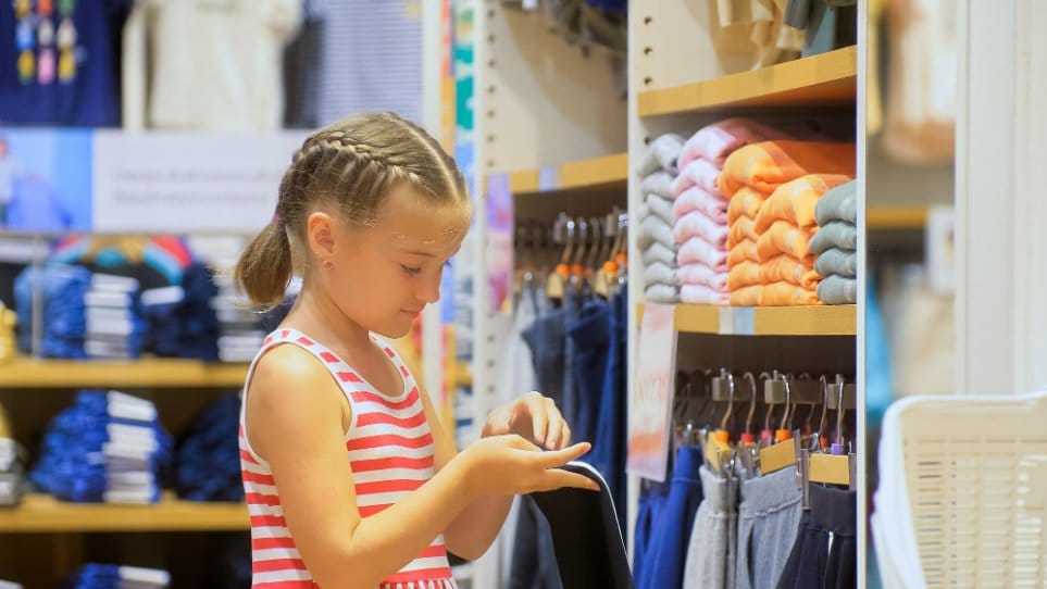 A little girl looking for clothes in clothing store cheerfully