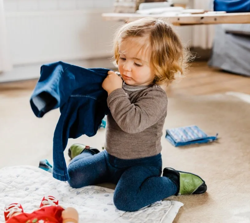 Toddler independently putting on clothes with easy-to-use features like elastic waistbands and simple closures