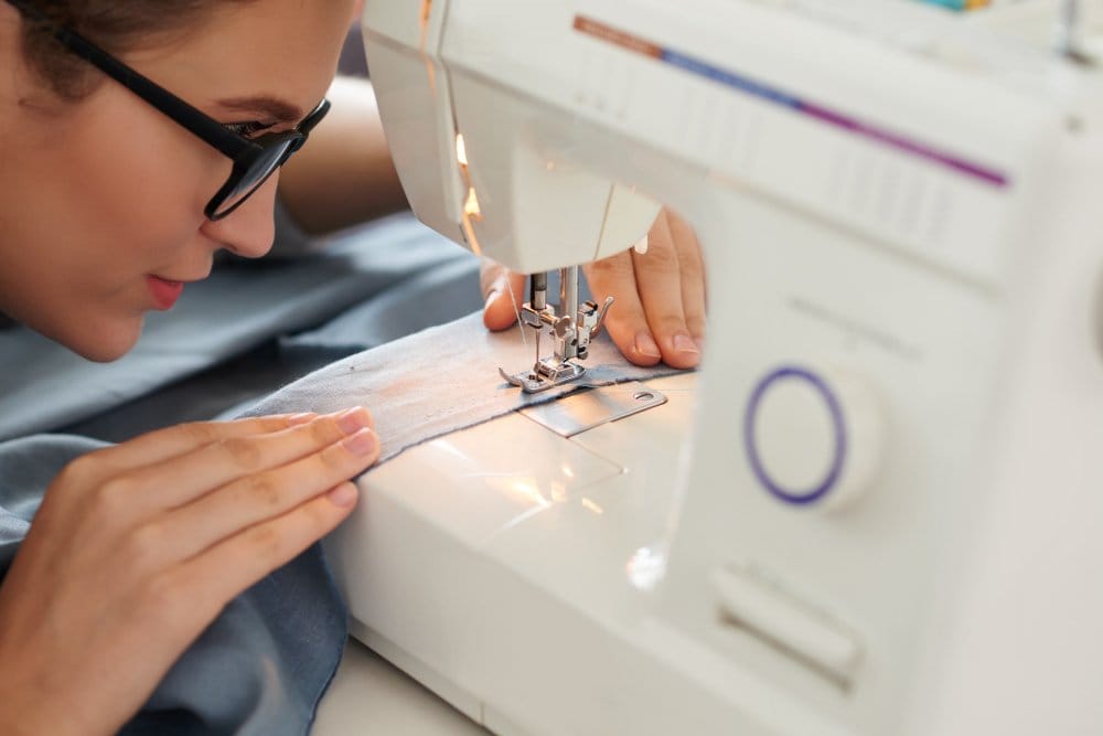 woman paying very close attention while sewing a hem