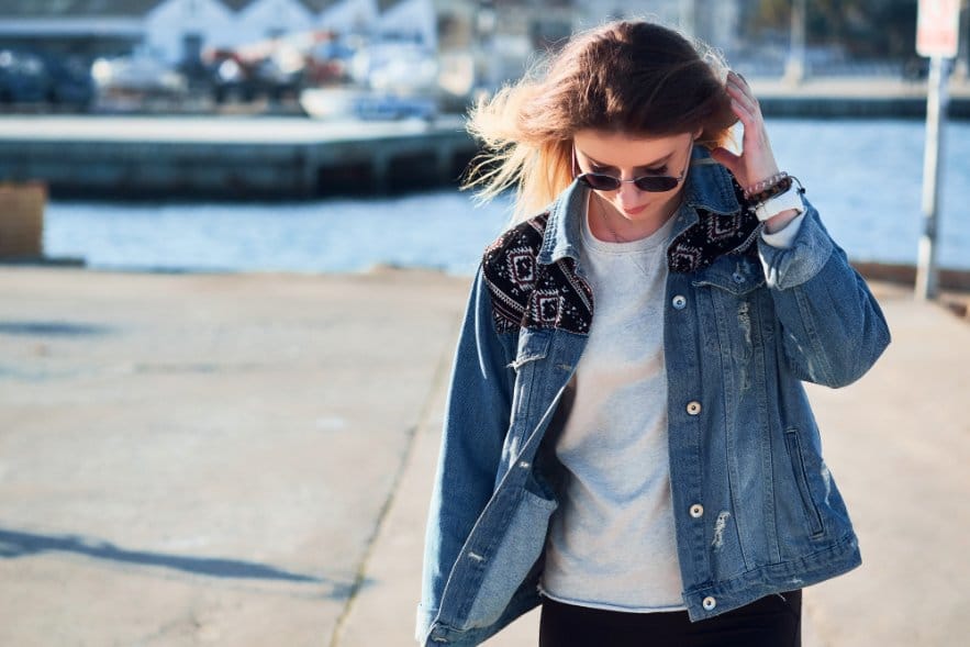 A woman wearing a denim jacket and sun glasses