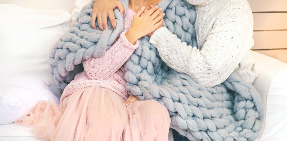 couple sitting on a chair cuddling a soft wool fabric
