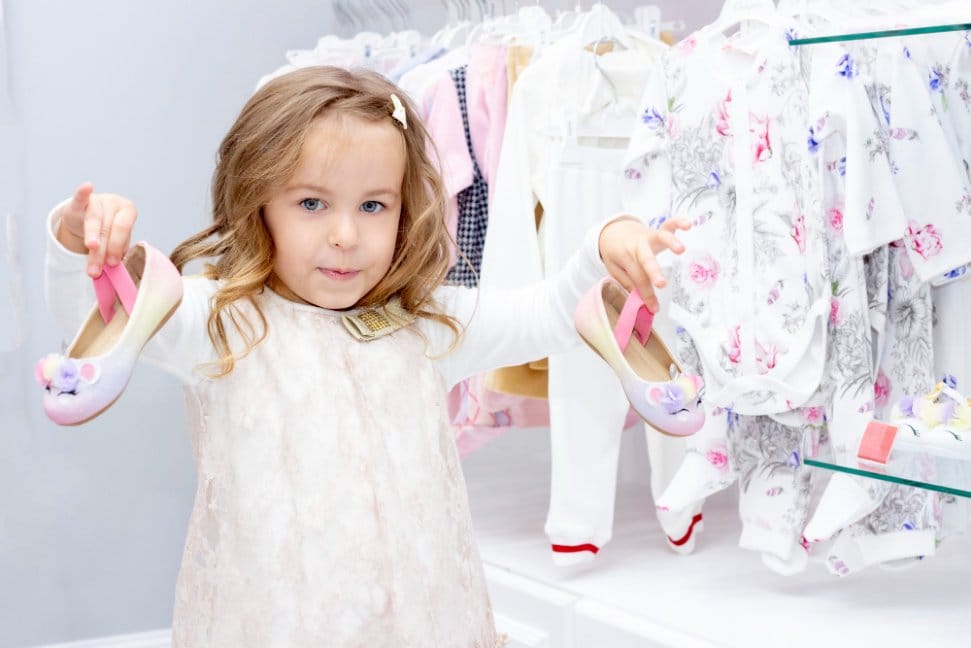 Little girl in a clothing shop holding shoes
