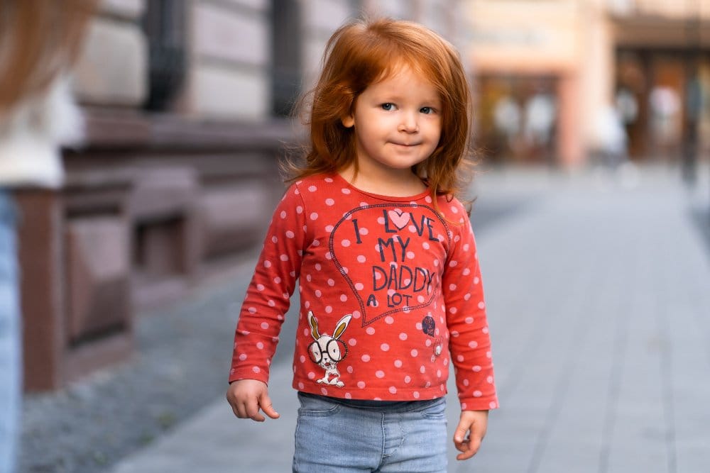 Smiling little girl wearing a cute outfit that says "I love my daddy a lot"