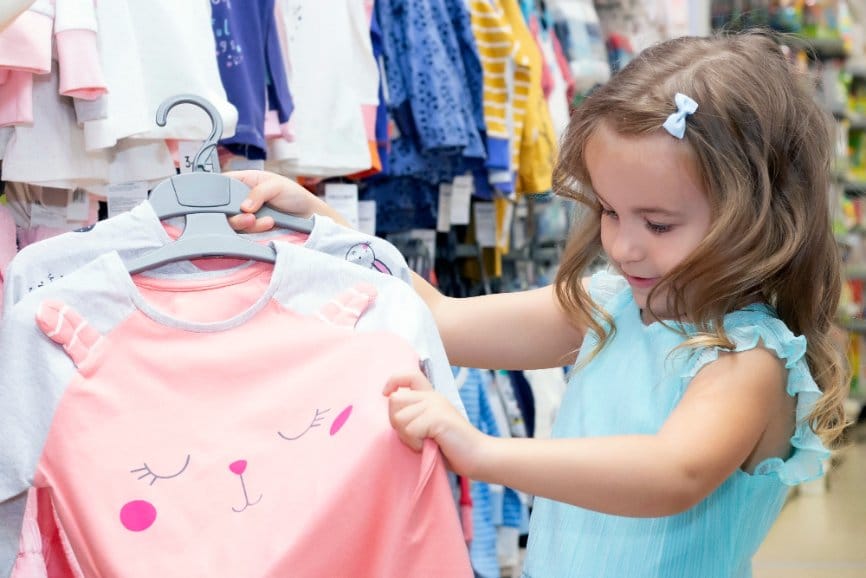 Little girl checking out a top in a clothing store