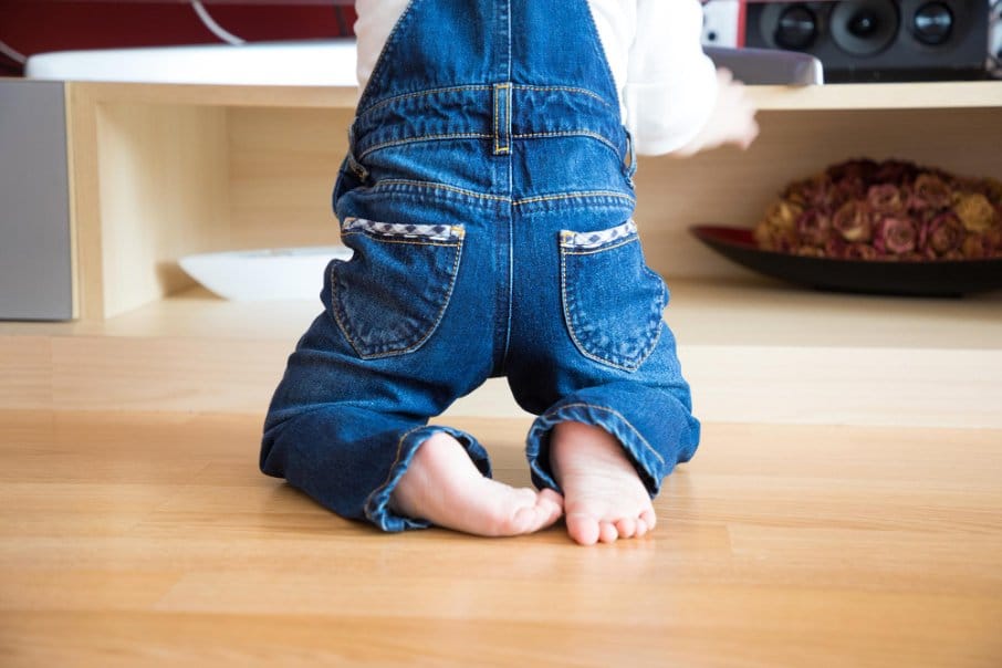 Toddler kneeling in front of a shelf