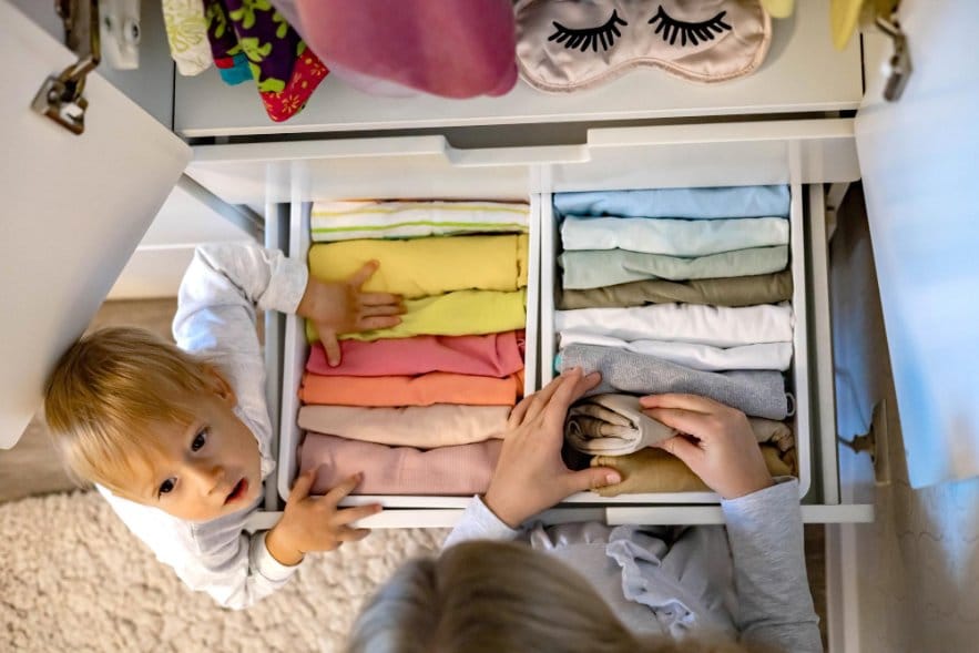 Little siblings selected clothes from an organised clothing drawer