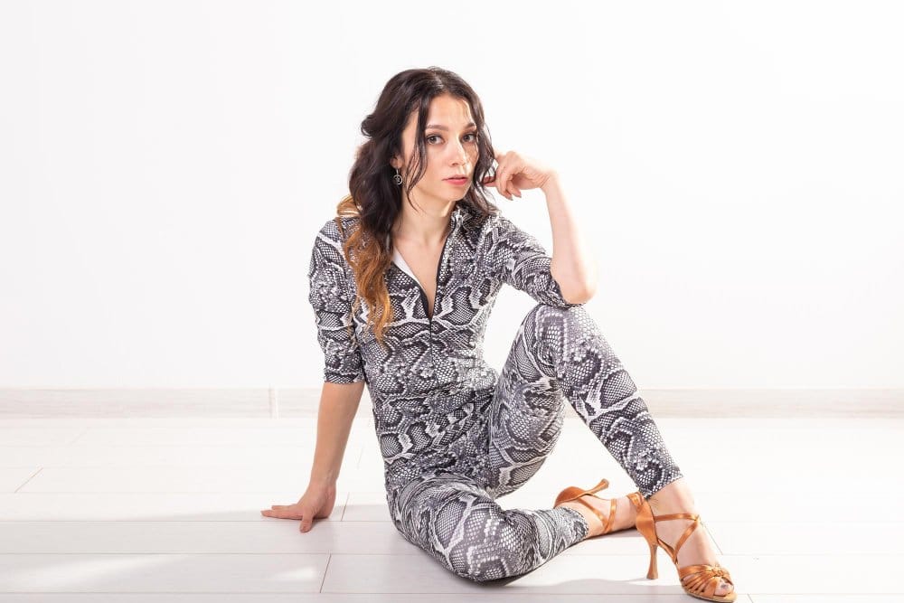 A woman wearing snake print jumpsuit sitting on the floor