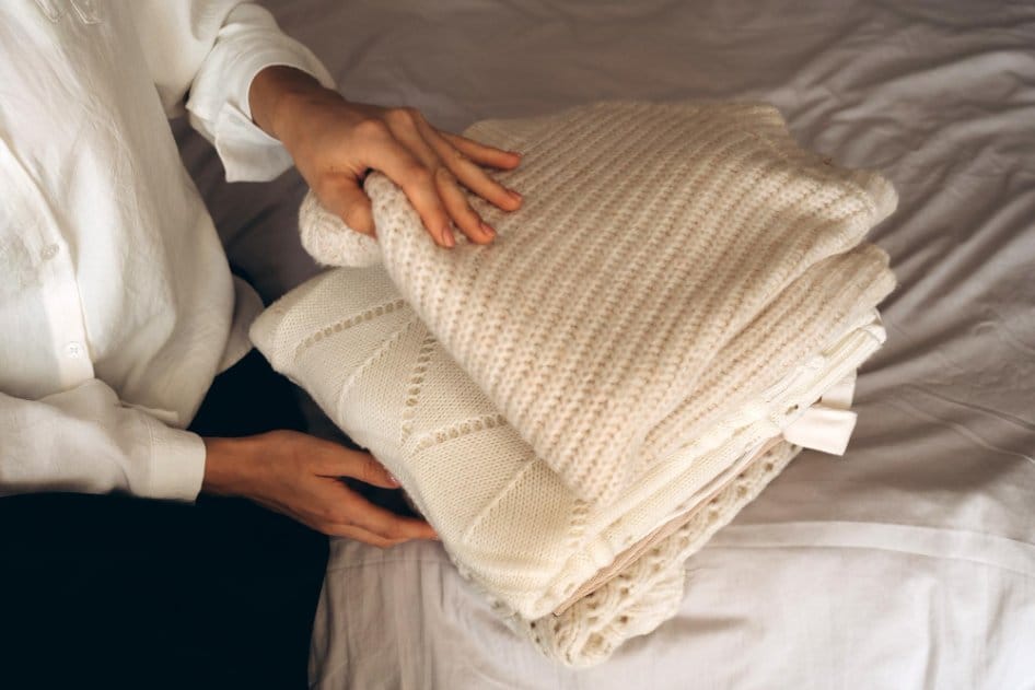 A woman folding soft cashmere sweaters ready for storage