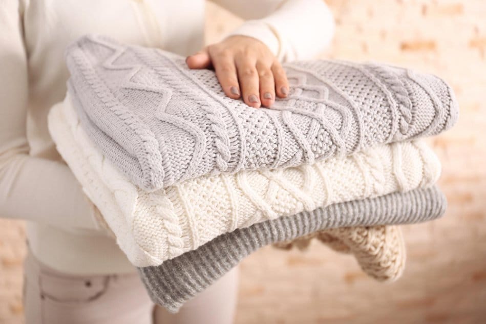 A laundry working carrying folded cashmere sweaters