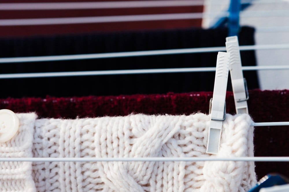 Cashmere sweater being air-dried on a clothing rack