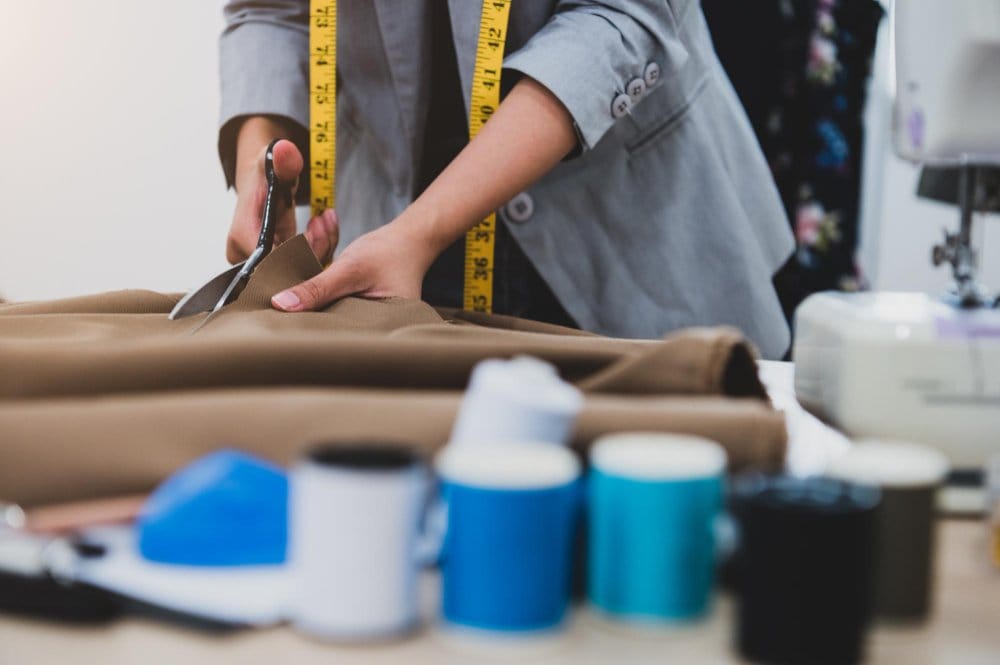 A tailor cutting fabrics to use in sewing a pair of pants