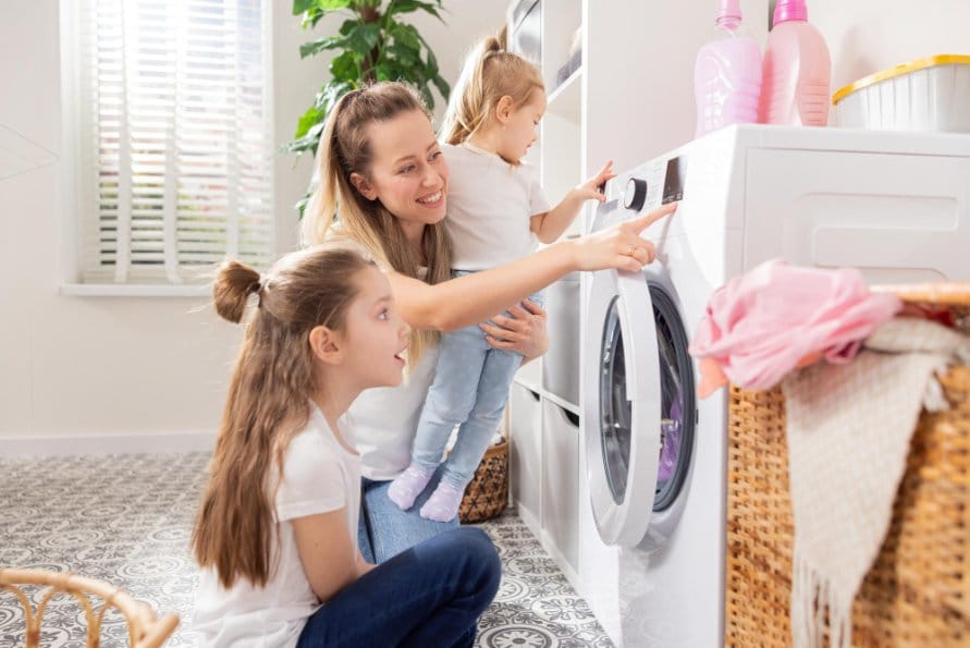 Mother and two children starting washing machine together