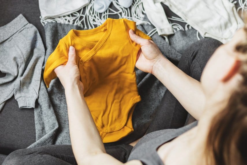 A pregnant woman preparing baby outfits