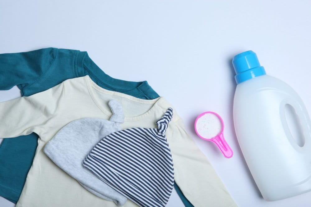 Baby clothes and detergents on a colored background