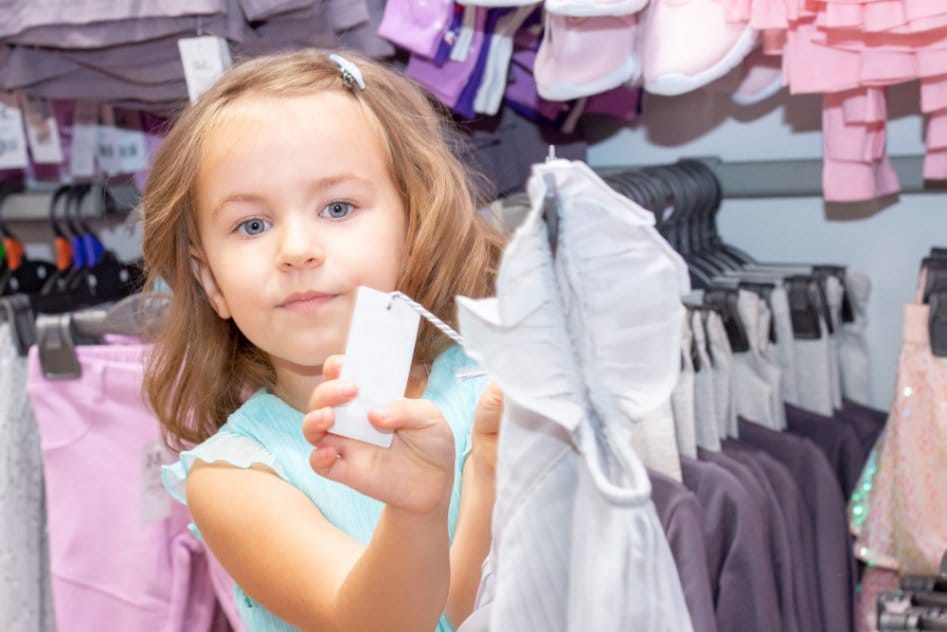 Little girl showing the label of an outfit in a shop